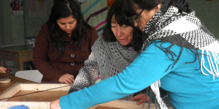 Una voluntaria enseña a tejer a mujeres en la comuna de Colina.